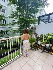 uma mulher de pé numa varanda a olhar para as plantas em 1BR at Trees Residences with Balcony em Quezon City