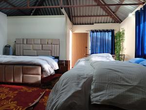达兰萨拉Hill Ventures Adventure Camp and Restaurant的一间有两张床和蓝色窗帘的卧室