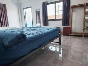 a bedroom with a bed with blue sheets and windows at Sawasdee Home in Betong +9 photos