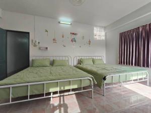 a bedroom with two beds with green sheets at Sawasdee Home in Betong