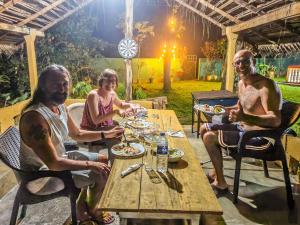 a group of people sitting around a wooden table at Sharta Unawatuna Hostel in Unawatuna