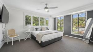 a white bedroom with a bed and windows at Brunswick Beach Club - Coastal Comfort Near Beach in Coffs Harbour