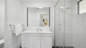 a white bathroom with a sink and a shower at Brunswick Beach Club - Coastal Comfort Near Beach in Coffs Harbour