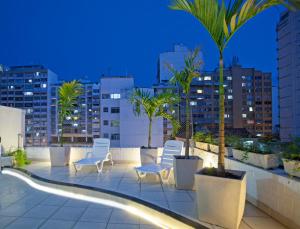 a rooftop patio with chairs and palm trees at night at Hotel Village Icaraí in Niterói