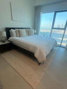 アブダビにあるLuxury Saadiyat Fully Equipped Apartmentの大きなベッドと大きな窓のある寝室