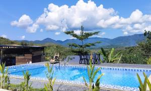 a swimming pool with mountains in the background at CBHResort Agrofarm in Kampong Benchah Tualang