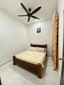 a bedroom with a bed with a ceiling fan at HasYaa Homestay in Kampong Bukit Kuang