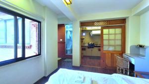 a bedroom with a bed and a kitchen with a window at Tiny Haven Apartment at Greentara Heritage Home in Pātan