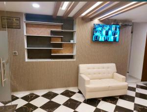 a living room with a white chair and a tv at Reside Inn in Bangalore
