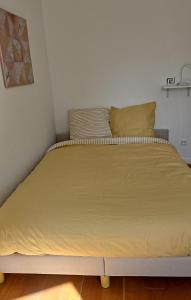 a bed in a bedroom with a yellow blanket on it at Amber room - 20 min to Paris in Créteil