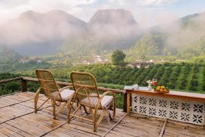 two chairs on a deck with a view of mountains at Akha PhamiO อาข่า พามิโอ้ in Ban Pha Mi