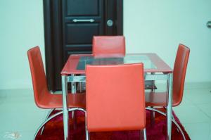 a table with four red chairs around it at The Montrose Apartment in Asaba