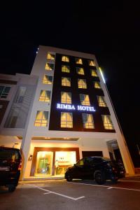 a hotel with two cars parked in a parking lot at Rimba Hotel in Kuala Terengganu