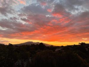 a sunset with a mountain in the background at Mountain View Studio in Raglan +3 photos