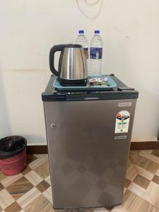 a tea kettle and water bottles on top of a refrigerator at Calangute Beach Prime in Calangute +22 photos