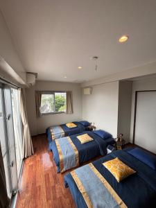 three beds in a room with blue sheets at The Villa Lino in Yomitan