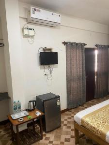 a room with a bed and a table and a tv at Calangute Beach Prime in Calangute