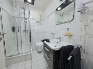 a white bathroom with a shower and a sink at Bentheimer Hof in Hagen