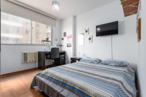 a bedroom with a bed and a desk and a television at Praia de Icarai a 500m in Niterói