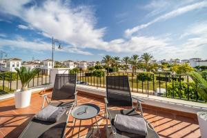 Un patio con dos sillas y una mesa en un balcón. en Villa mit privatem Pool, zentrumsnah, en Roldán
