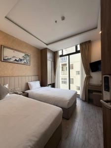 ニャチャンにあるAngel Hotelのベッドが2つと窓があるホテルの部屋
