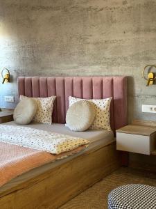 a bed with a pink headboard and pillows on it at Stari Toranj VI studio apartman in Vukovar