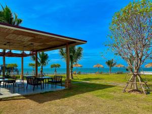 un pavillon avec tables et chaises sur la plage dans l'établissement Charome Resort, à Ban Suan On