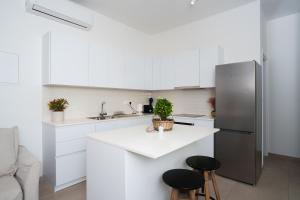 a kitchen with white cabinets and a refrigerator at WealthyStays 2BR Retreat , 5Min Walk to Beach in Protaras