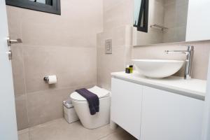 a white bathroom with a sink and a toilet at WealthyStays 2BR Retreat , 5Min Walk to Beach in Protaras