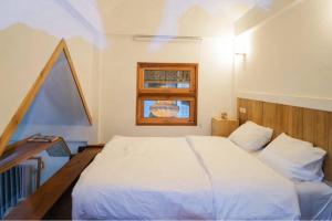 um quarto com uma cama branca e uma janela em อาข่า พามิโอ้ em Ban Pha Mi mais 1 fotografia