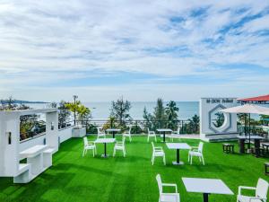 a patio with white tables and chairs and the ocean at Mzion Hotel Weligama in Weligama