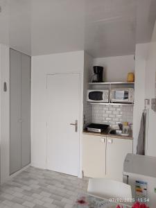 a kitchen with white cabinets and a white door at Studio cabine le grau du roi 6 min de la plage à pied in Le Grau-du-Roi