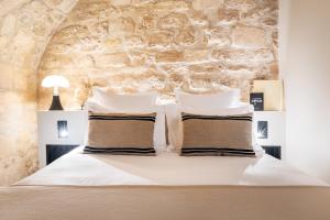 ein Schlafzimmer mit einem weißen Bett und einer Steinmauer in der Unterkunft Luxury Suite 2BR in Charming Courtyard Le Marais in Paris