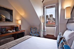 a bedroom with a bed, chair and a window at TURIM Terreiro do Paço Hotel in Lisbon