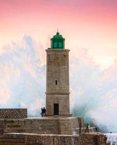 un faro con un hombre corriendo delante de él en La Cassy - Sleep in Cassis, en Cassis