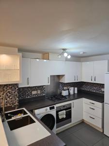 eine Küche mit weißen Schränken und einem Herd mit Backofen in der Unterkunft Ensuite Doubleroom with Private Toilet and Bathroom in central Dartford in Dartford