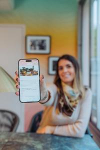 a woman sitting at a table holding up a cell phone at Kyriad Cannes - Mandelieu in Cannes