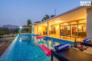 a swimming pool with chairs and a house at StayVista at Beyond Infinity with Hill View, BBQ in Lonavala