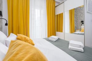 sypialnia z łóżkiem z żółtymi zasłonami i lustrem w obiekcie Wola Cozy Apartment by P&O Apartments w Warszawie