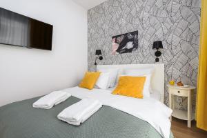 sypialnia z łóżkiem z białą pościelą i żółtymi poduszkami w obiekcie Wola Cozy Apartment by P&O Apartments w Warszawie
