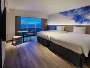 a hotel room with two beds and a table at Grand Mercure Okinawa Cape Zanpa Resort in Yomitan