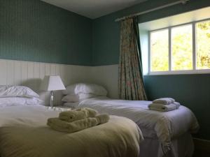 a bedroom with two beds with towels on them at Swiss Cottage in Ballindalloch