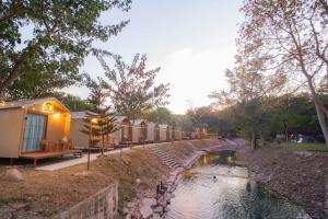 a row of cottages next to a river at Season camp cha-om in Kaeng Khoi