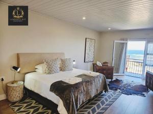 ein Schlafzimmer mit einem Bett und einem Balkon mit Meerblick in der Unterkunft Lambertsbay Beachfront in Lambertʼs Bay