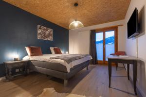 a bedroom with a bed and a desk and a television at La Forge de Diogne - luxury and cosy B&B Alpine lodge in Crans-Montana