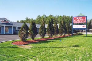 a sign for a red car park with trees in a yard at Red Carpet Inn & Suites Hammonton - Atlantic City in Hammonton