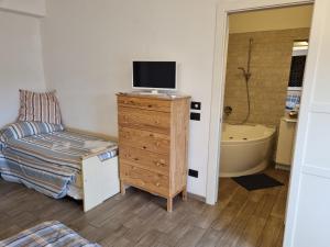 a bedroom with a television on a dresser with a tub at B&B La Terrazza Sui Fieschi in Cogorno