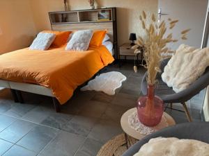 a bedroom with a bed with an orange comforter and a vase at La croisée des chemins in Vions