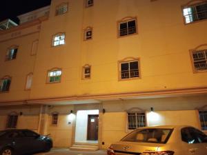 two cars parked in front of a building at night at 1 Separate Bedroom and Attached Bathroom in a shared apartment in Muscat