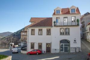 a red car parked in front of a white house at Casa das Faias - Serra da Estrela in Manteigas
